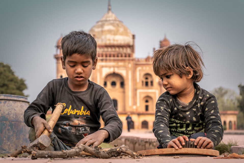 Two poor children sitting in front of the Taj Mahal